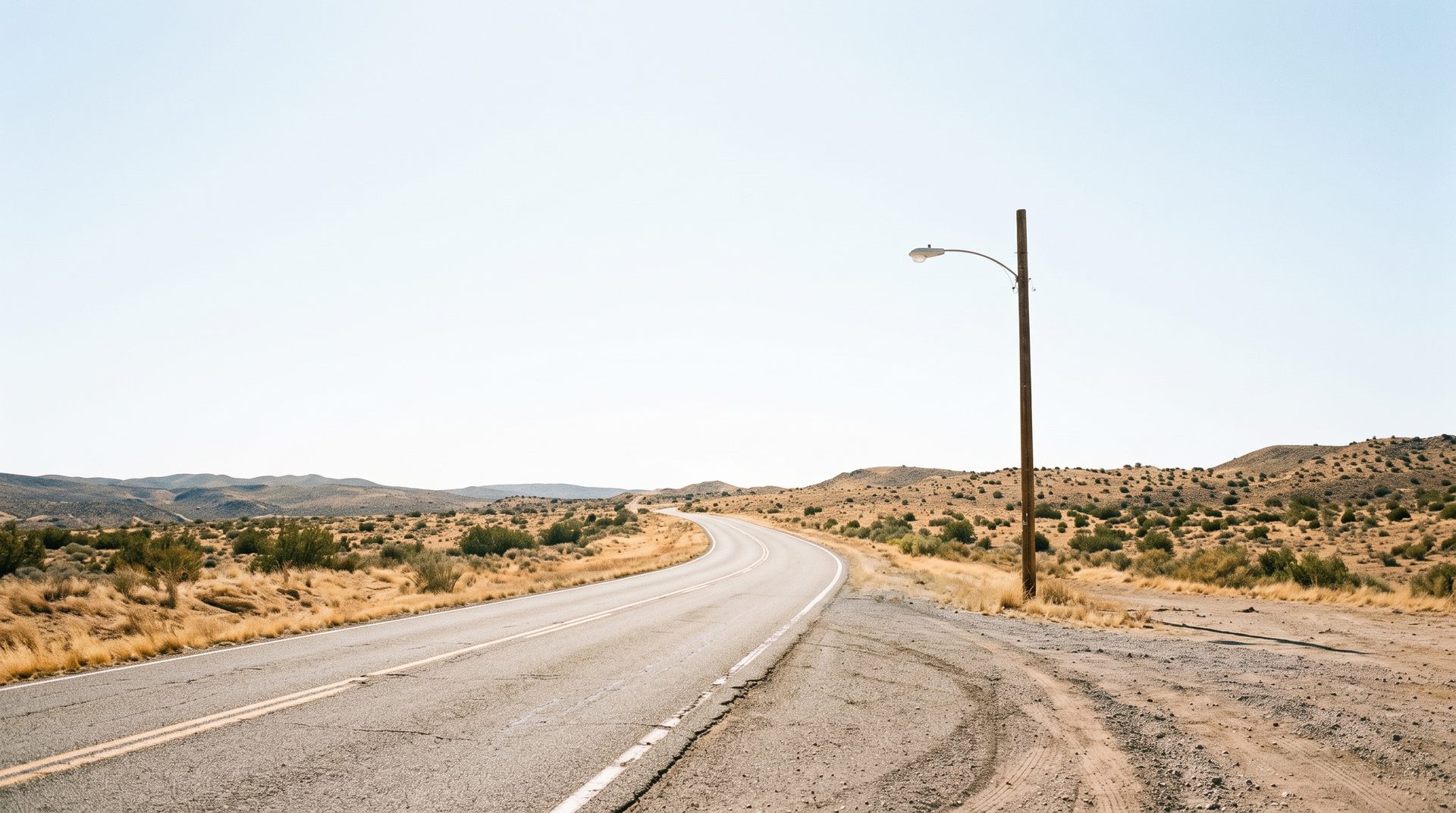 The same empty two-lane road in daylight